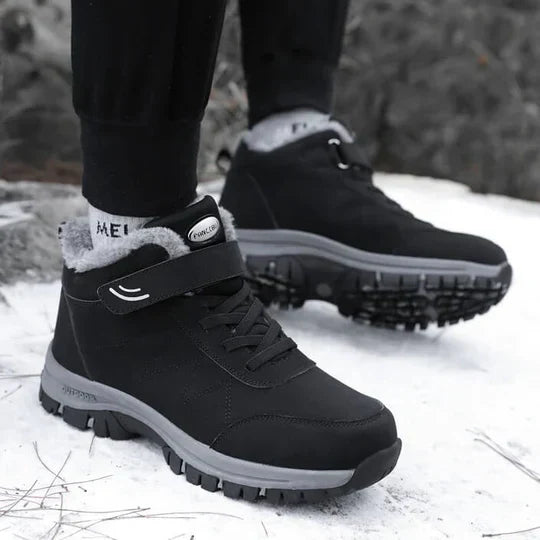 Schwarze Stiefel an den Füßen einer Person, die im Schnee steht, mit sichtbarem Fellkragen 4