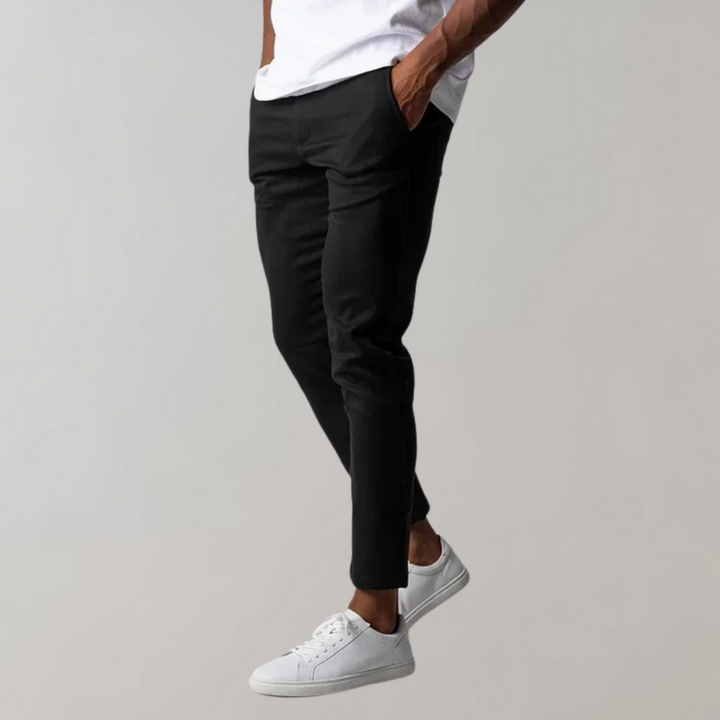 Mann trägt schwarze Chinohose und weiße Sneaker, lässiger Stil, Herrenmode.