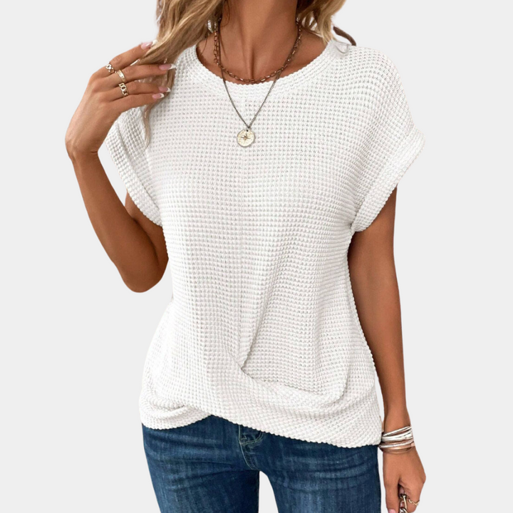 Frau trägt weißes Strickoberteil, lässig, modisch, mit Schmuck, ideal für Freizeitkleidung.