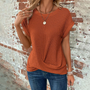 Frau in orangefarbenem Strickpullover vor Backsteinwand, lässiger Stil, modisch.
