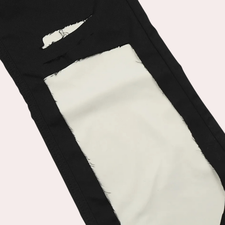 Schwarze Jeans mit weißem, rechteckigem Riss-Detail, modische zerrissene Denim-Hose.