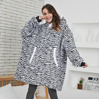 Frau in übergroßem Zebra-Pullover, gemütlich, schwarz-weiß, Kapuze, Wohnzimmer.