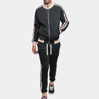 Mann in schwarzem Trainingsanzug mit Streifen, Reißverschlussjacke, Freizeithose, Sneakers.