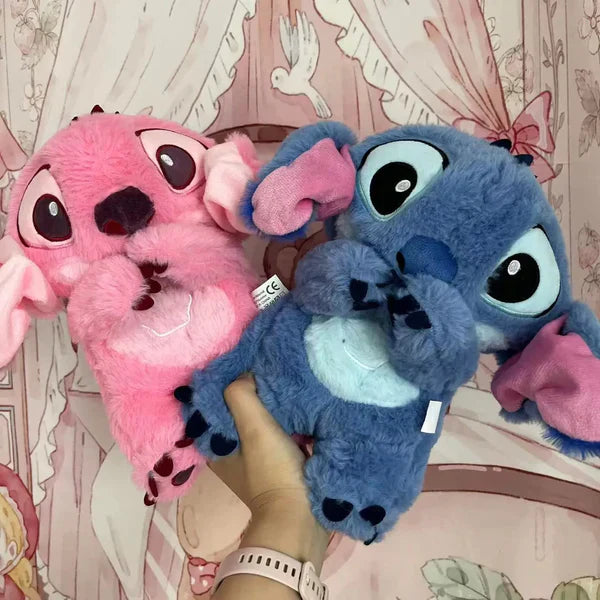 Zwei Plüschtiere, rosa und blau, mit großen Augen, vor einem gemusterten Hintergrund.