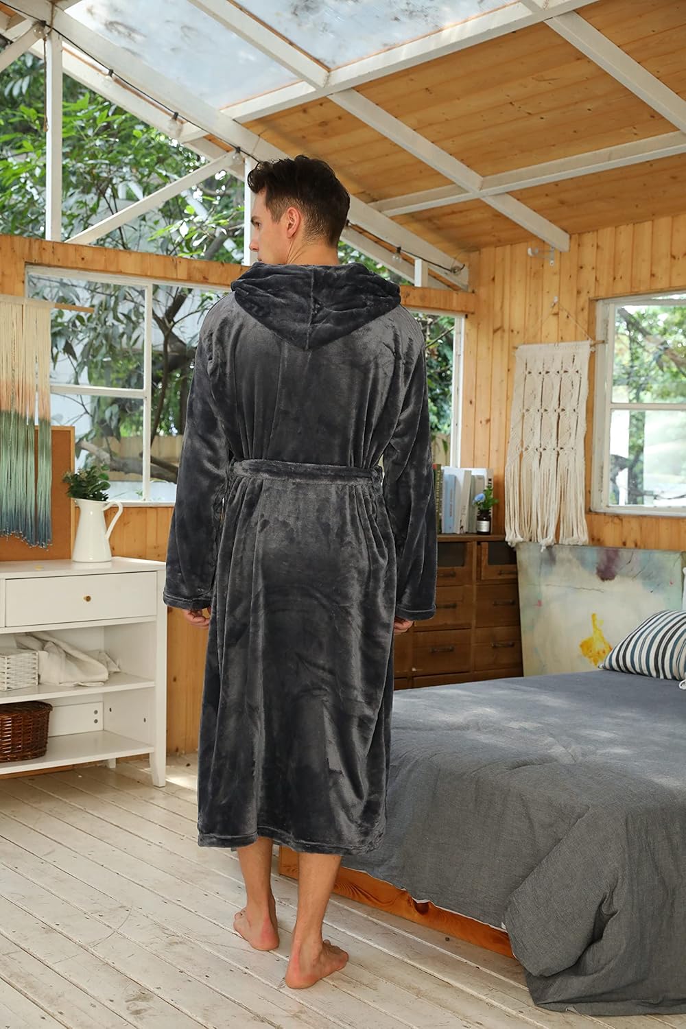 Rückansicht des dunkelgrauen Bademantels mit Kapuze und Gürtel, Model in einem Holzraum mit Bett 39