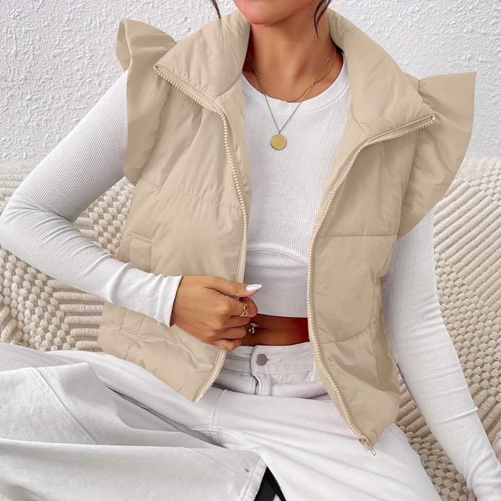 Frau in beiger Steppweste mit Rüschen, weißem Langarmshirt, modisch, gemütlich, Herbstmode.