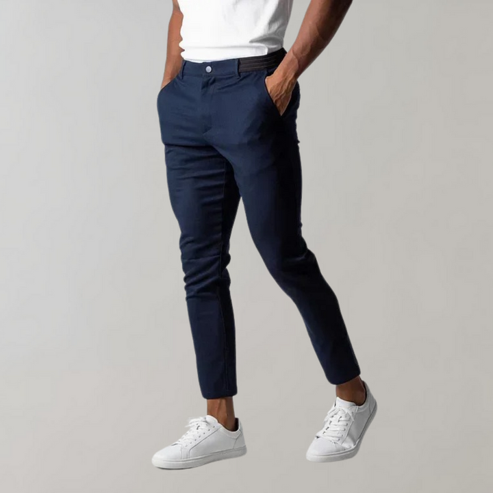 Mann trägt dunkelblaue Chinohose, weiße Sneaker, lässiger Stil, Herrenmode.