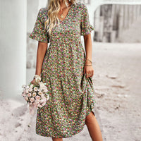 Frau in geblümtem Midikleid, hält Rosenstrauß, Sommermode, grün, elegant, Freizeitkleidung.
