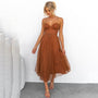 Blonde Frau in braunem, festlichem Midikleid mit Spaghettiträgern vor weißem Hintergrund.