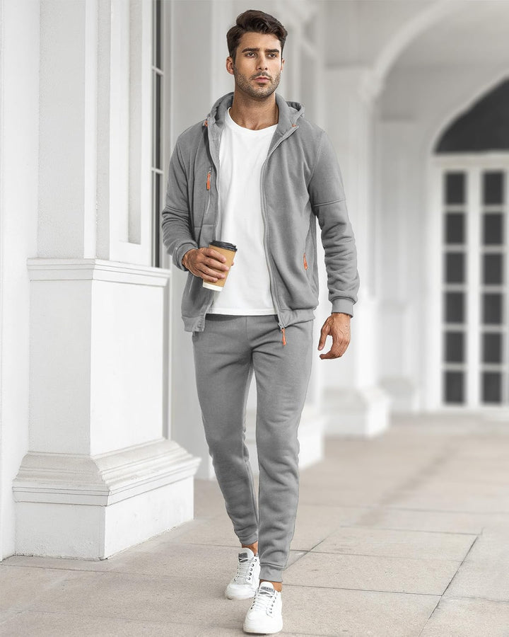 Model im grauen Anzug mit offener Jacke über weißem T-Shirt, hält einen Kaffeebecher im Säulengang 30