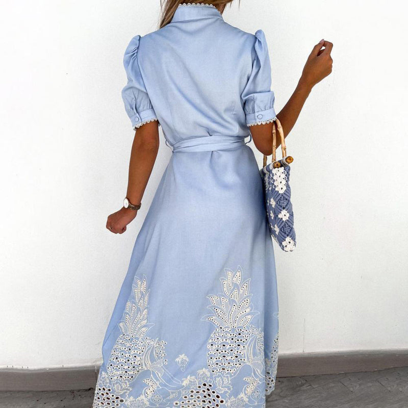 Frau in hellblauem Maxikleid mit Spitze, trägt eine gemusterte Tasche, elegantes Sommeroutfit.