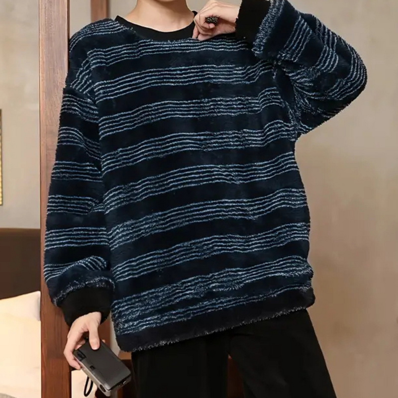 Person in gestreiftem, blau-schwarzem Fleece-Pullover, hält eine Kamera in der Hand.