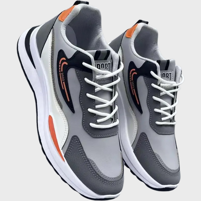 Graue Sportschuhe mit weißen Schnürsenkeln, orange Akzenten, atmungsaktivem Material.
