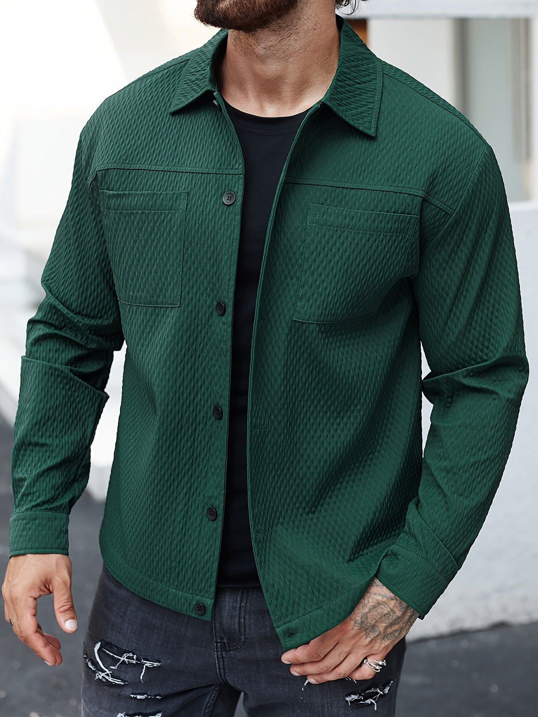Mann in grüner Steppjacke, schwarze Jeans, lässiger Look, Herrenmode, Outdoor-Bekleidung.