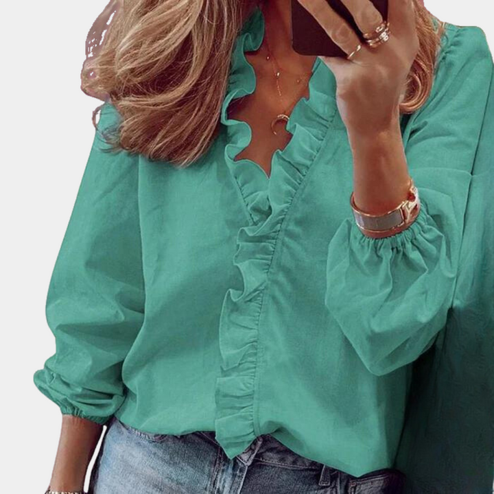 Frau in grüner Rüschenbluse, Smartphone haltend, modisch, lässig, Damenmode, Alltagslook.
