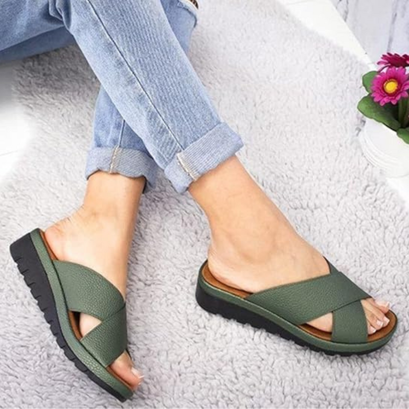 Grüne Damen-Sandalen mit Kreuzriemen, bequeme Sommerschuhe auf Teppich.
