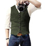 Mann in grünem Wollgilet mit Kamera, weißem Hemd und blauer Jeans.