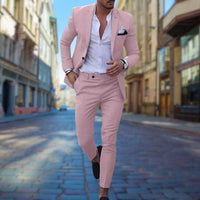 Mann im rosa Slim-Fit-Anzug auf Kopfsteinpflasterstraße, elegantes Herrenmode-Outfit.