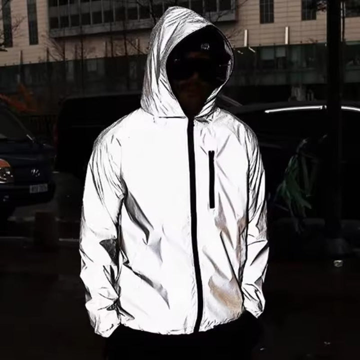 Person mit Kapuze und Sonnenbrille trägt die reflektierende Jacke nachts auf einer Straße, Hände in den Taschen 3