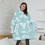Frau in blau-weißem Oversize-Hoodie mit Wolkenmuster, gemütliche Kleidung, Wohnzimmer.
