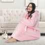 Frau in rosa Kuscheldecke mit Kapuze auf Sofa, gemütlich, Katze, Wohnzimmer, Wintermode.