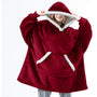 Frau in rotem, übergroßem Hoodie-Decke mit Kapuze und Tasche, gemütliche Winterbekleidung.