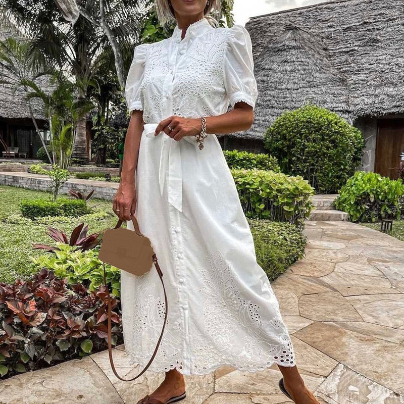 Frau in weißem Spitzen-Maxikleid im Garten, Sommermode, elegantes Design, kurze Ärmel.