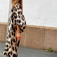 Frau im langen, beige-schwarzen Leopardenmuster-Kleid auf der Straße.