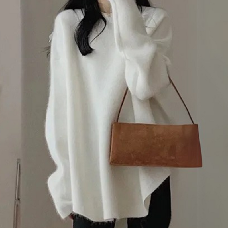 Frau in weißem Oversize-Pullover mit brauner Ledertasche, modisch, elegant, Herbstmode.