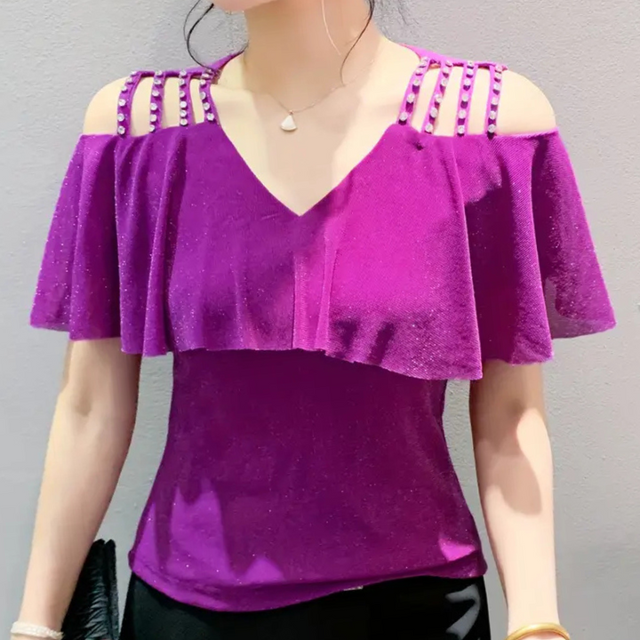 Frau in lila schulterfreiem Top mit Perlenverzierung, elegantes Abendoutfit.