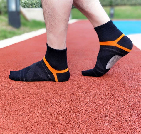 Beine eines Mannes in schwarzen Socken mit orangefarbenen Details auf einer roten Laufbahn 3