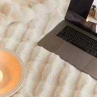 Nahaufnahme der weichen cremefarbenen Plüschdecke mit Laptop und Kerzenschale im Anschnitt 8