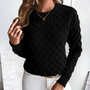 Frau in schwarzem Strickpullover mit Punktmuster, goldene Halskette, weiße Hose.